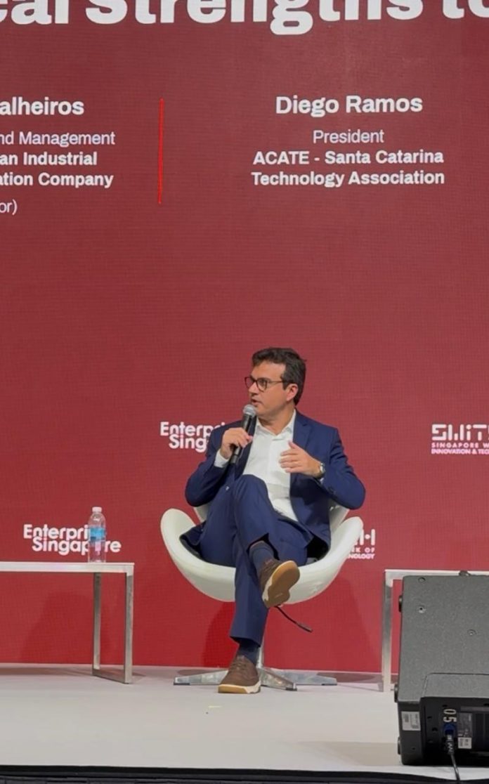 Diego Ramos, presidente da ACATE, fala ao microfone sentado em poltrona branca no palco do SWITCH, em Singapura