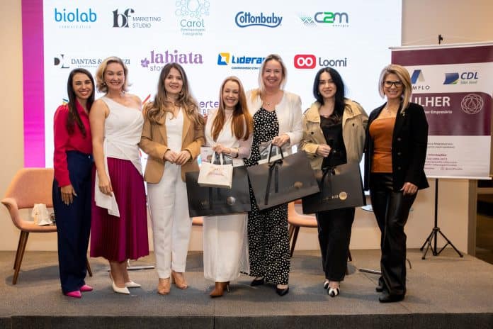 Mulheres empresárias e convidadas posam no palco do encontro Além do Rosa da AEMFLO e CDL São José