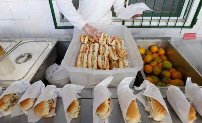Merendeira organiza sanduíches e laranjas na cozinha de escola estadual em Santa Catarina