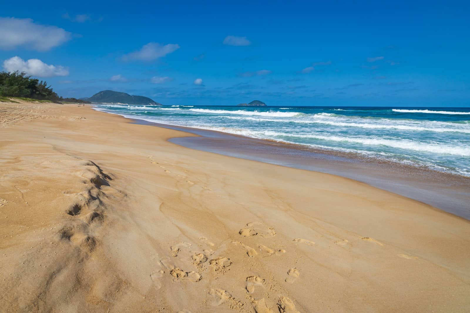 Faixa de areia da Praia do Moçambique, em Florianópolis, com pegadas e o mar ao fundo