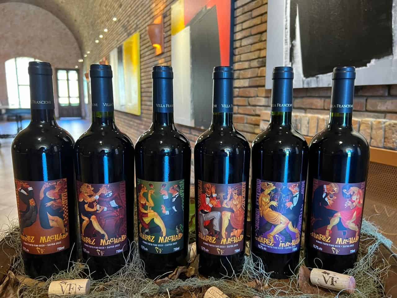 Seis garrafas de vinho com rótulos coloridos ilustrados por Juarez Machado