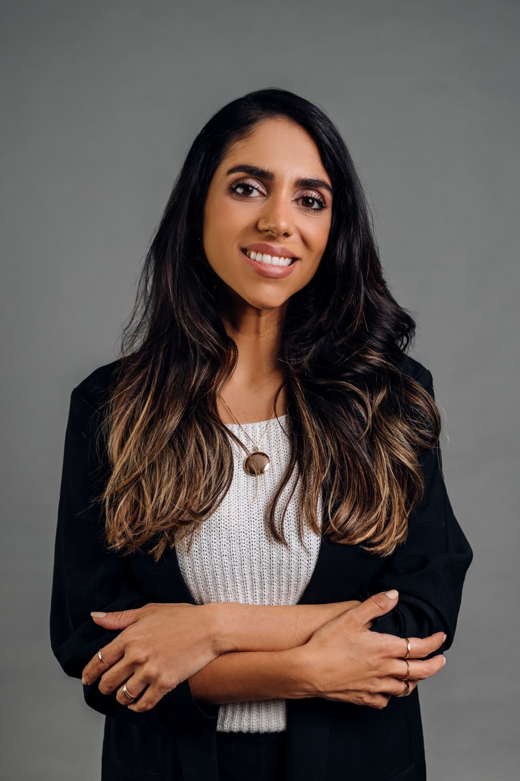 Retrato de Thaísa Durso, especialista em finanças pessoais, de braços cruzados e blazer preto