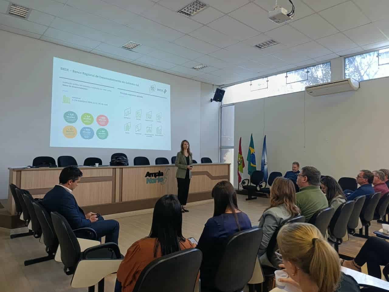 Apresentação do BRDE projetada em telão para prefeitos e técnicos na reunião de abertura em Mafra