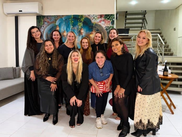 Grupo de mulheres empreendedoras posa sorridente na estreia do Clube Entre Taças Floripa, com painel de inspiração árabe ao fundo