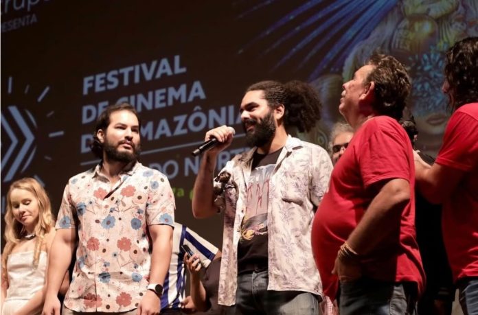 Integrantes da equipe do curta Mata-Gato no palco de um festival de cinema, um deles falando ao microfone