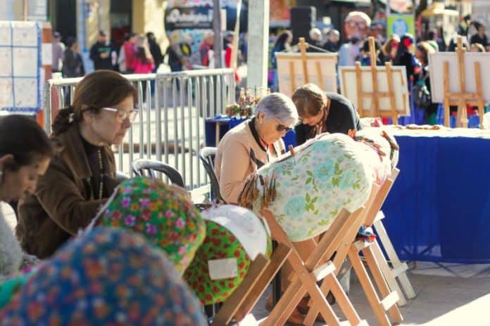 Rendeiras trabalham com bilros em almofadas coloridas em evento ao ar livre em Florianópolis
