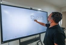 Dia do Professor: Governo de SC anuncia gratificação de R$ 3 mil, nova tabela salarial e mais vagas de mestrado para 55 mil docentes Professor escreve a palavra Educação em tela interativa de sala de aula da rede estadual de Santa Catarina