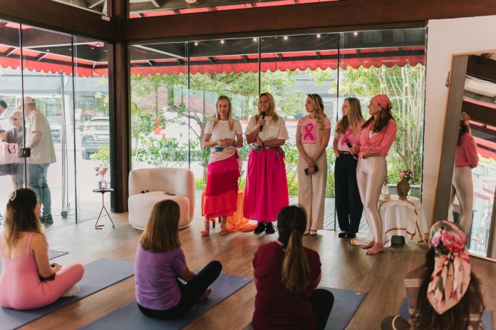 Organizadoras e palestrantes vestidas de rosa falam ao público sentado em tapetes de yoga no Dia Rosa do Shopping Casa & Design