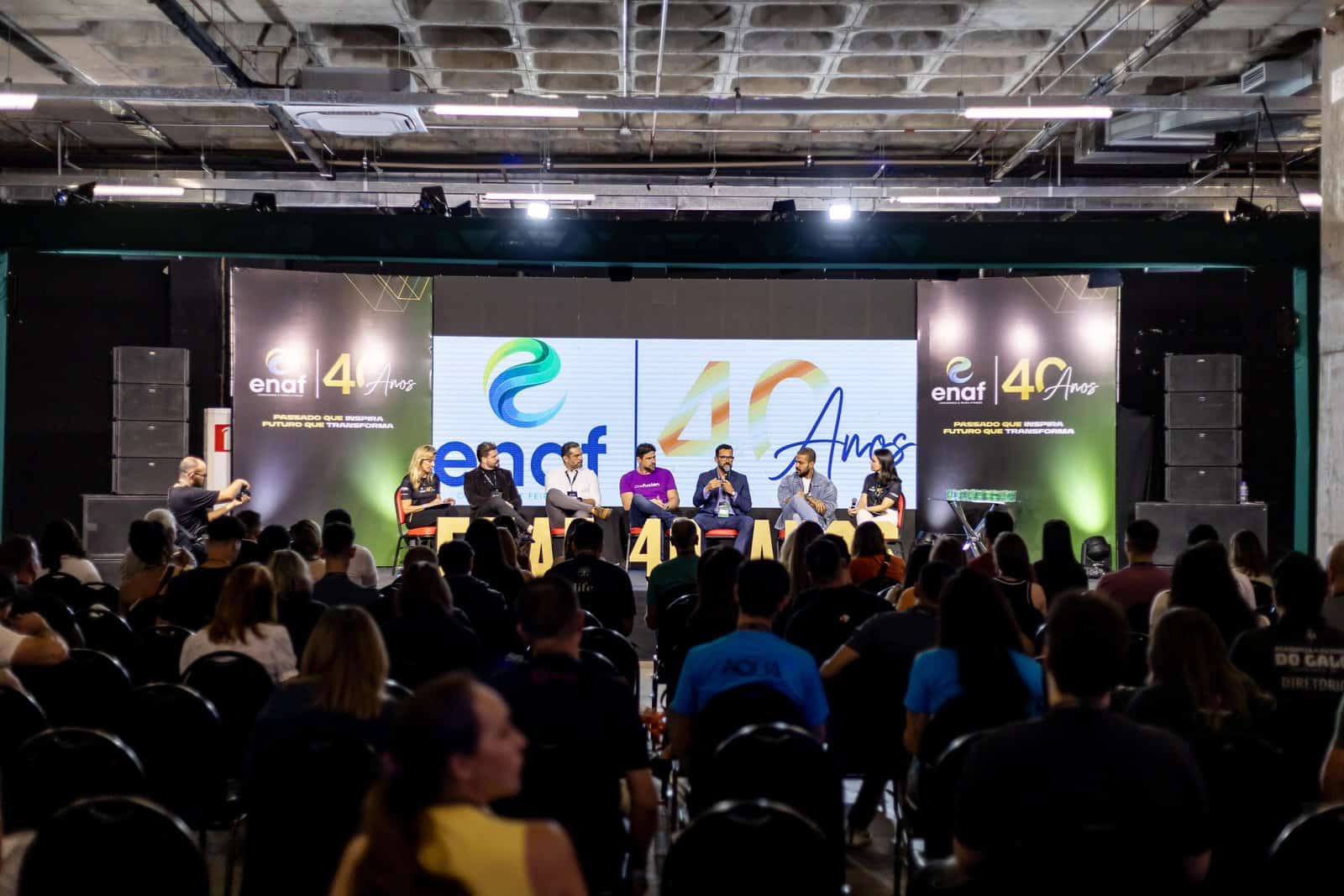Painel com sete convidados no palco do ENAF diante da plateia