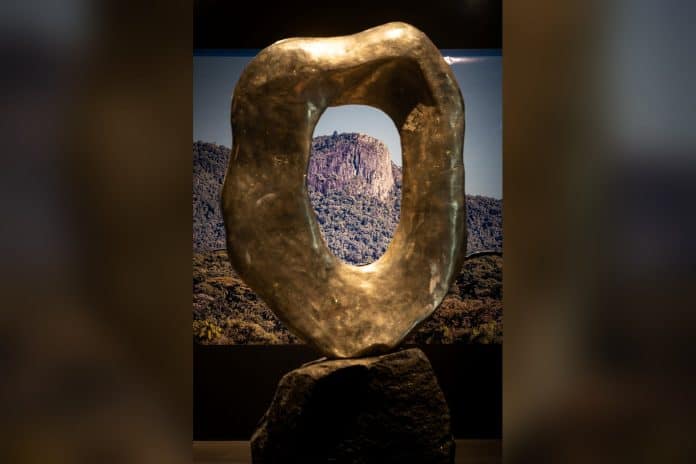 Escultura em bronze vazada de Denise Milan diante de fotografia da Pedra Branca na A.Galeria
