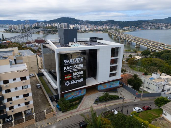 Vista aérea do prédio sede da FACISC em Florianópolis, com as pontes e a Ilha de Santa Catarina ao fundo