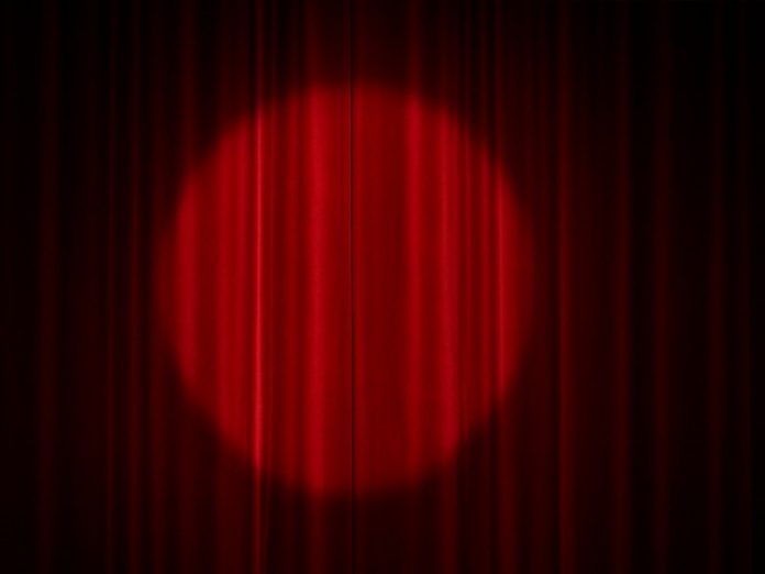 Cortina de teatro vermelha com um círculo de luz de refletor ao centro