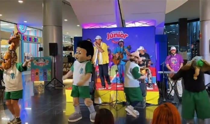 Personagens da Turma do Júnior dançam diante de banda em palco infantil montado no corredor de um shopping