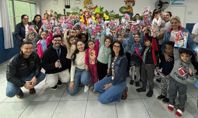 Crianças e adultos reunidos para foto em grupo em sala decorada, em ação da AEMFLO e CDL São José