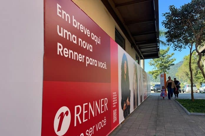 Tapume vermelho da Renner com a frase Em breve aqui uma nova Renner para você em corredor do Porto Belo Outlet Premium
