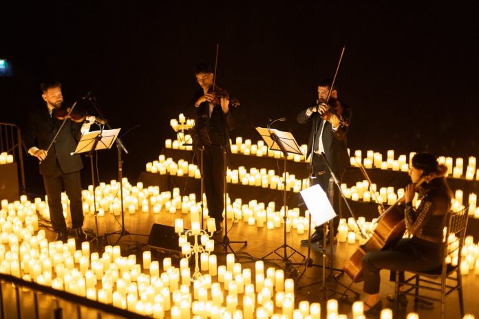 Quarteto de cordas toca em palco cercado por centenas de velas acesas em apresentação do Candlelight