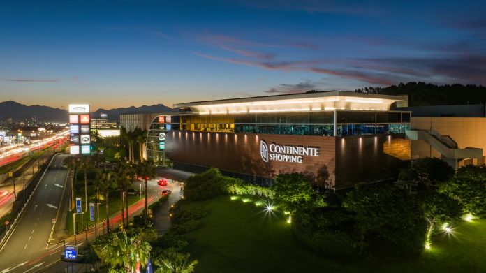 Fachada iluminada do Continente Shopping, em São José, ao entardecer