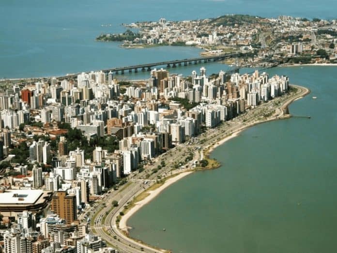 Vista aérea de Florianópolis com prédios da Beira-Mar Norte, a baía e a Ponte Hercílio Luz ao fundo