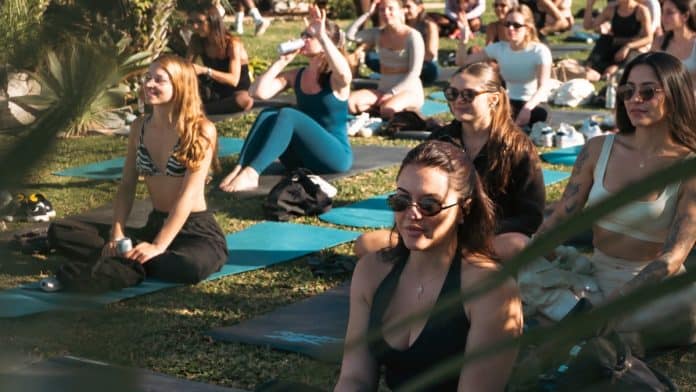 Participantes em tapetes de yoga ao ar livre durante encontro do Coffee Wellness & Club
