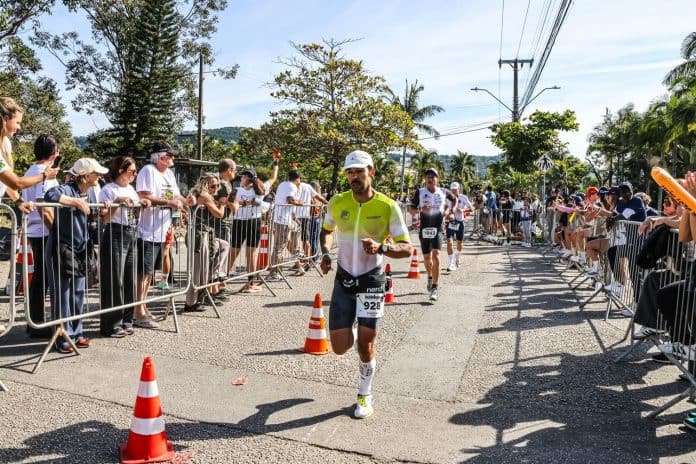Atleta corre entre o público na etapa de corrida do IRONMAN 70.3 Florianópolis