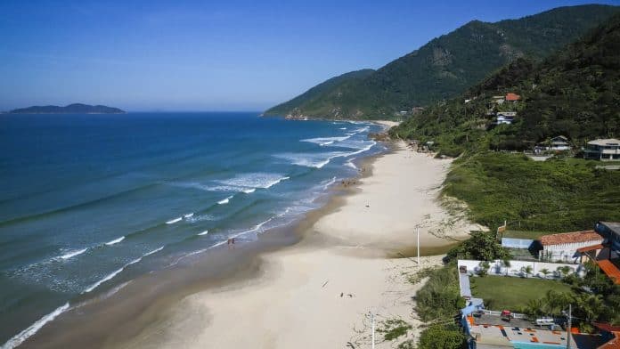 Vista aérea da Praia dos Açores, no Sul da Ilha, em Florianópolis, com faixa de areia, mar e morros com vegetação