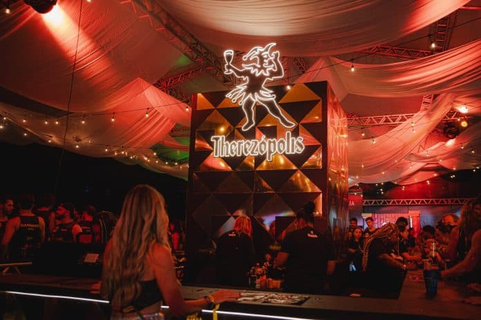 Bar da Therezópolis com letreiro iluminado e decoração de tecidos sob luz vermelha no Folianópolis