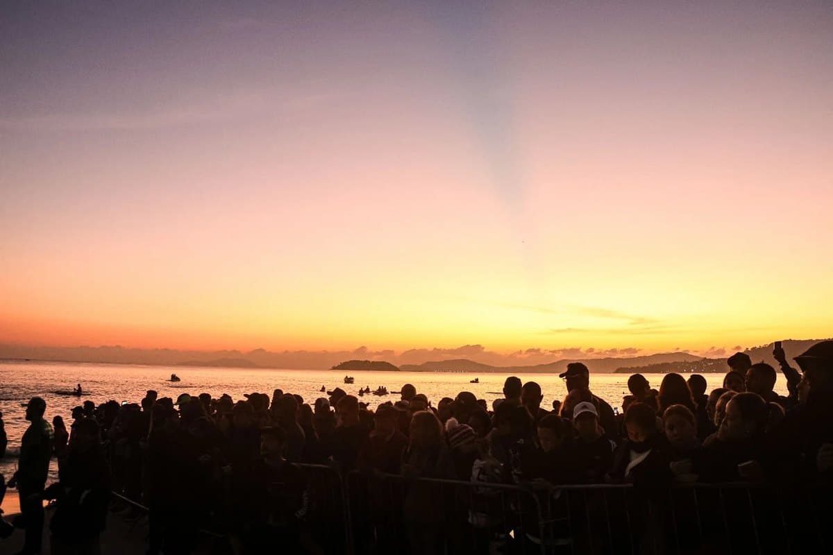 Público acompanha a largada do IRONMAN 70.3 Florianópolis ao amanhecer, na beira da praia