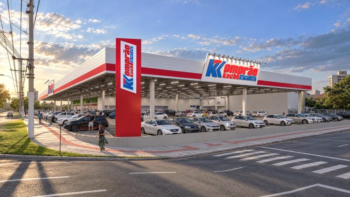 Projeção 3D da fachada da nova loja Komprão Koch Atacadista em Palhoça, com estacionamento coberto e totem vermelho com a marca