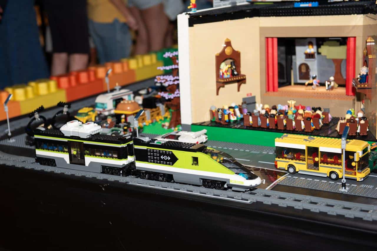 Trem, ônibus e teatro em miniatura montados com peças de LEGO na exposição Legueiros