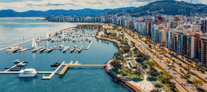 Projeção aérea da Marina Beira-Mar Norte, com píeres, barcos, parque na orla e prédios da avenida Beira-Mar Norte ao fundo