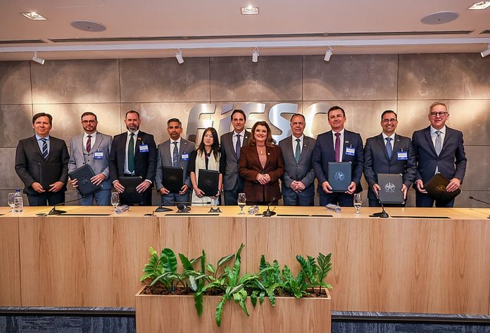 Embaixadores honorários de Santa Catarina e autoridades posam lado a lado, com pastas nas mãos, diante da parede com o logotipo da FIESC, em Florianópolis