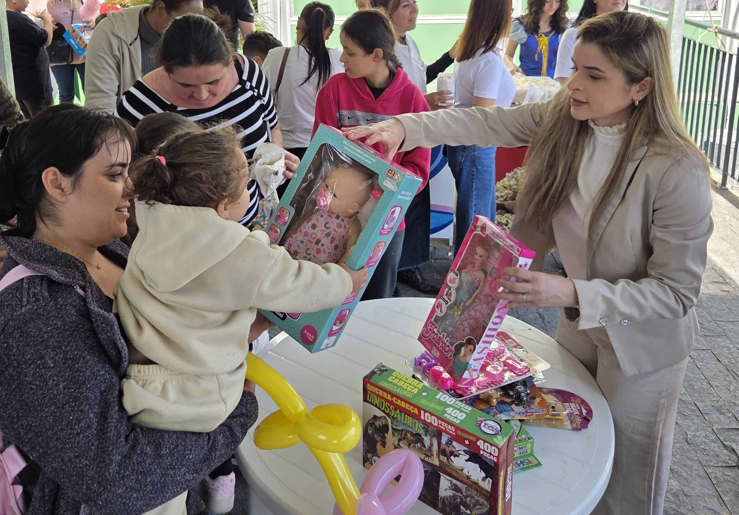 Francisca Araújo, da gestão do Square SC, entrega brinquedos a famílias na programação de Dia das Crianças da AVOS, em Florianópolis