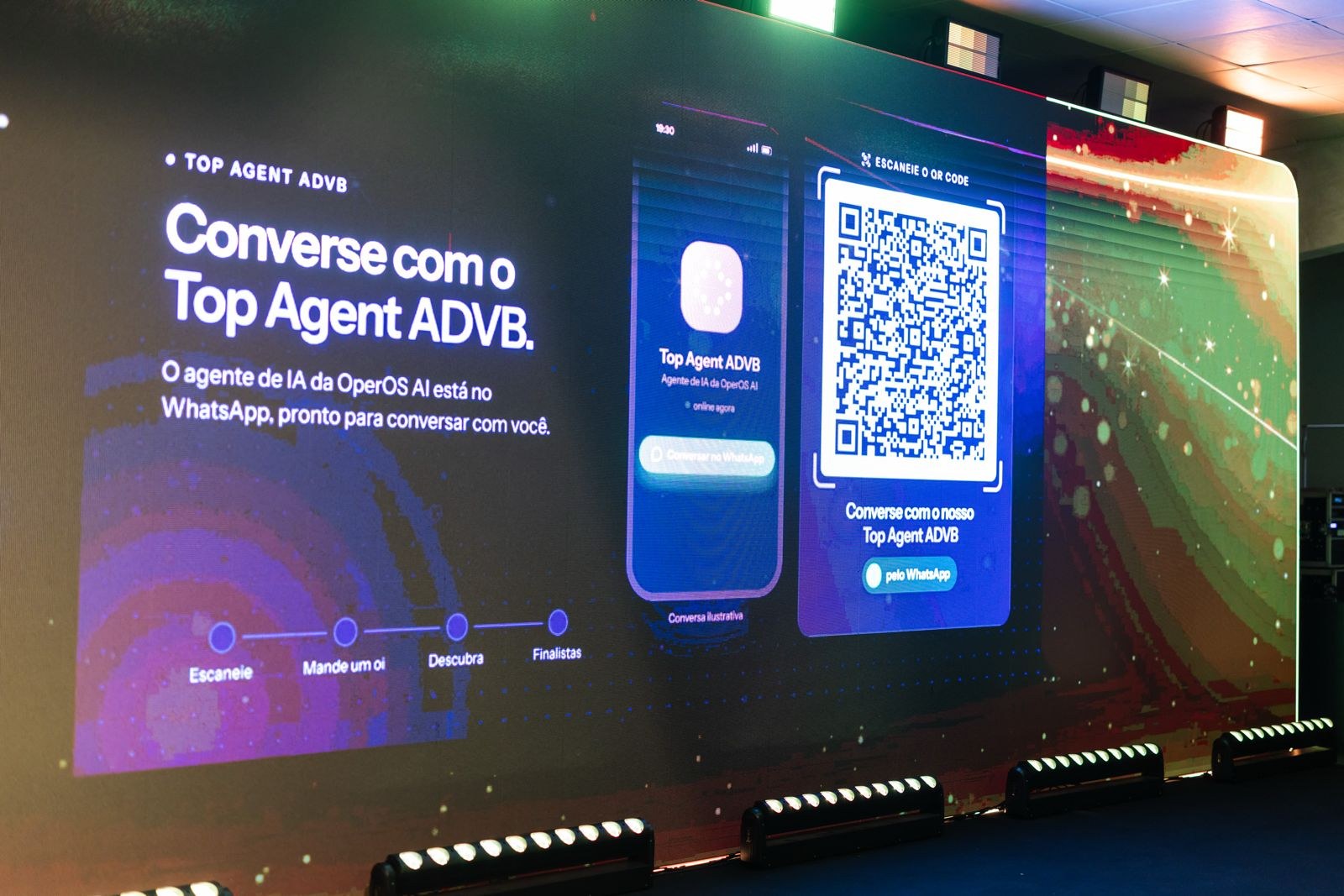 Telão do TOP de Marketing e Vendas ADVB/SC 2026 em Florianópolis com a frase Converse com o Top Agent ADVB, QR code e conversa de WhatsApp do agente de IA da OperOS AI