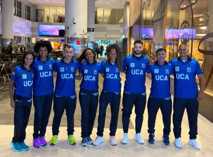Delegação da União Catarinense de Atletismo, com uniformes azuis da UCA, posa enfileirada em saguão de aeroporto