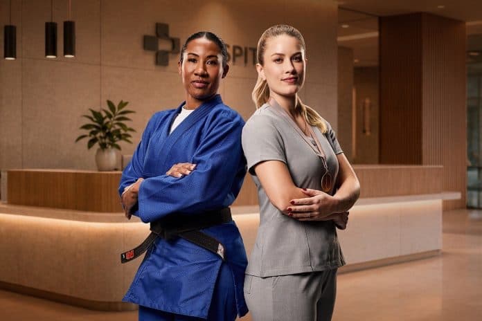 A judoca olímpica Ketleyn Quadros, de quimono azul, e a médica Marina Klein, de uniforme cinza, posam de braços cruzados em recepção de hospital
