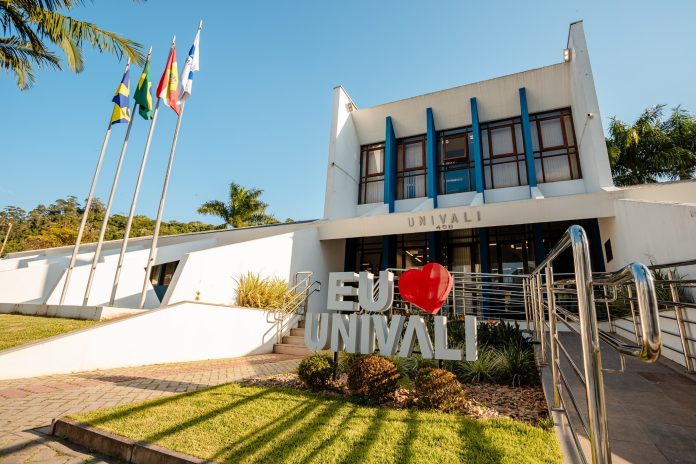 Fachada de prédio da Univali com bandeiras hasteadas e letreiro Eu amo Univali em frente à entrada